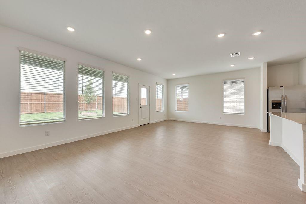 3009 Dutch Road Providence Village, TX 76227 - Photo 5 of 19 Open-concept living space featuring wood-finish flooring, recessed lighting, multiple windows with blinds, and a kitchen island with a light-toned countertop