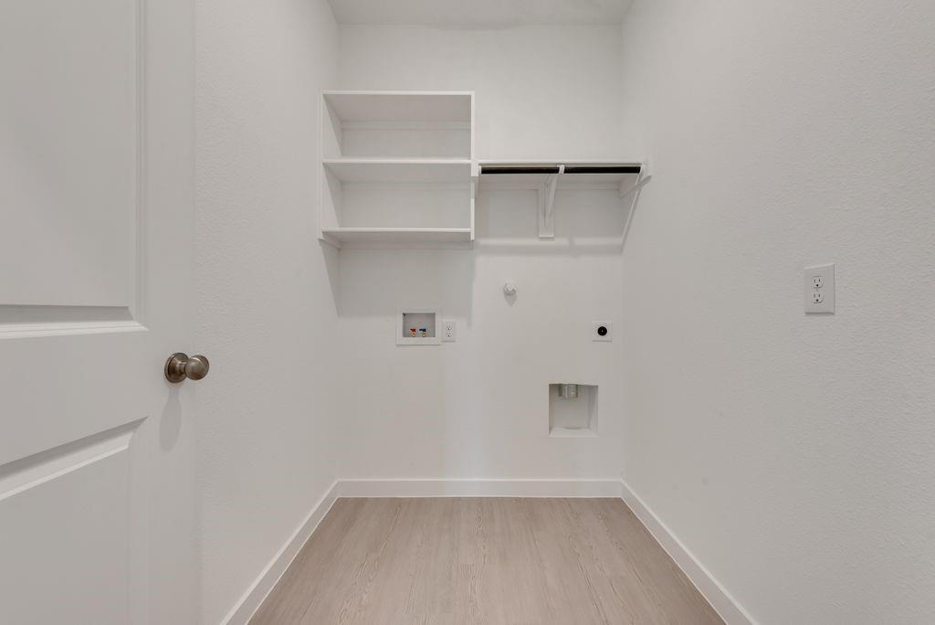 3009 Dutch Road Providence Village, TX 76227 - Photo 8 of 19 Utility room featuring wood-finish flooring, white walls, built-in shelving, and a clothing rod
