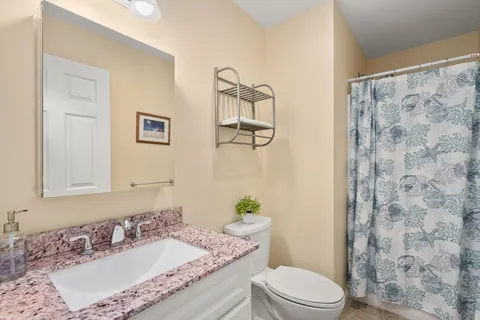 a bathroom with a granite countertop sink mirror vanity and toilet