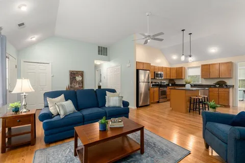 a living room with furniture kitchen view and a wooden floor
