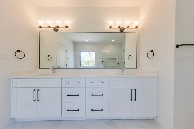 a spacious bathroom with a granite countertop sink a toilet a mirror and shower