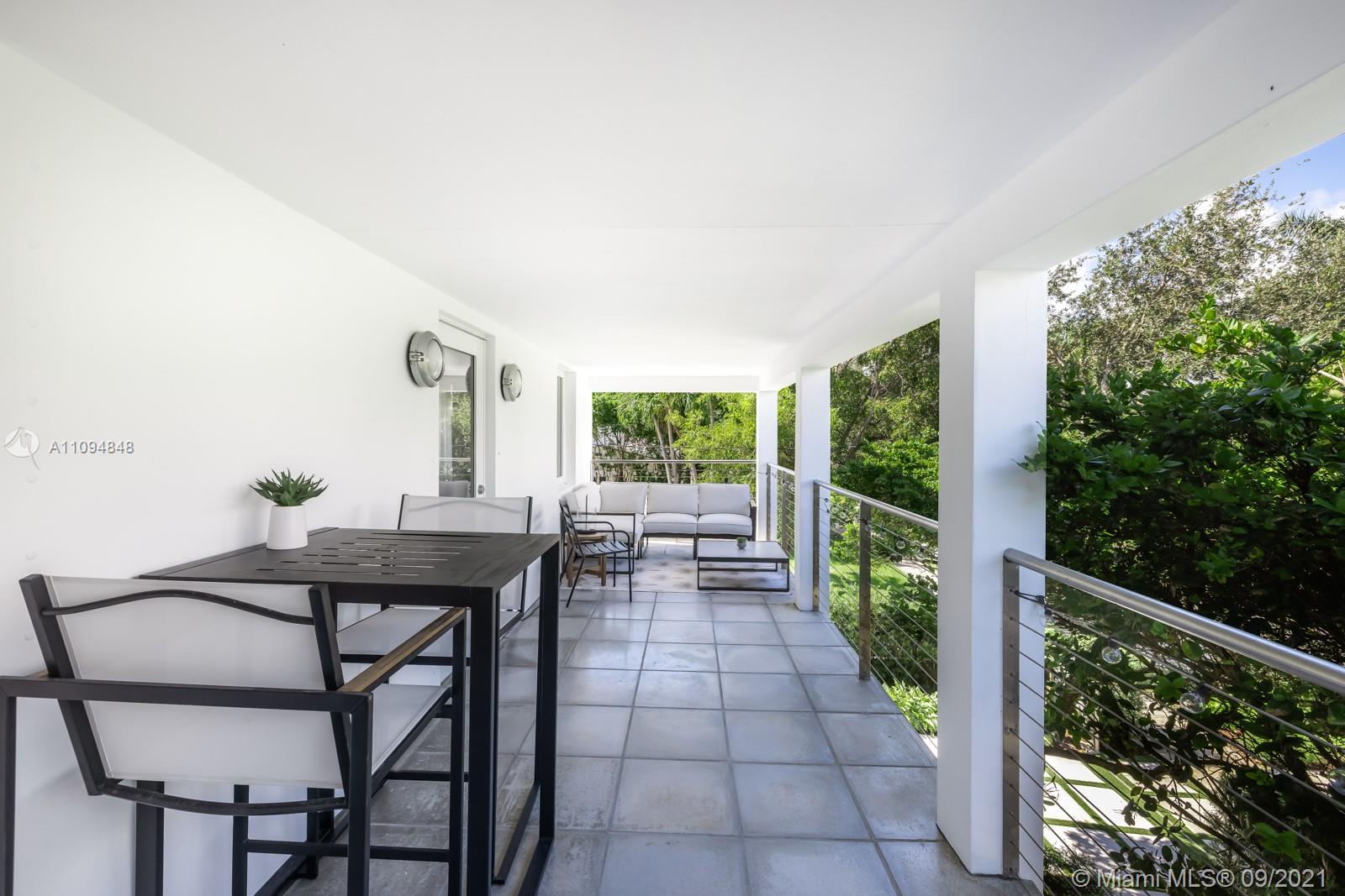 5235 North Bay Road Miami Beach, FL 33140 - Photo 20 of 22 a view of a patio with table and chairs with wooden floor and fence