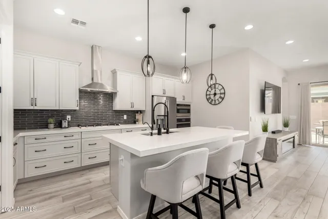 a kitchen with stainless steel appliances kitchen island granite countertop a table chairs and white cabinets