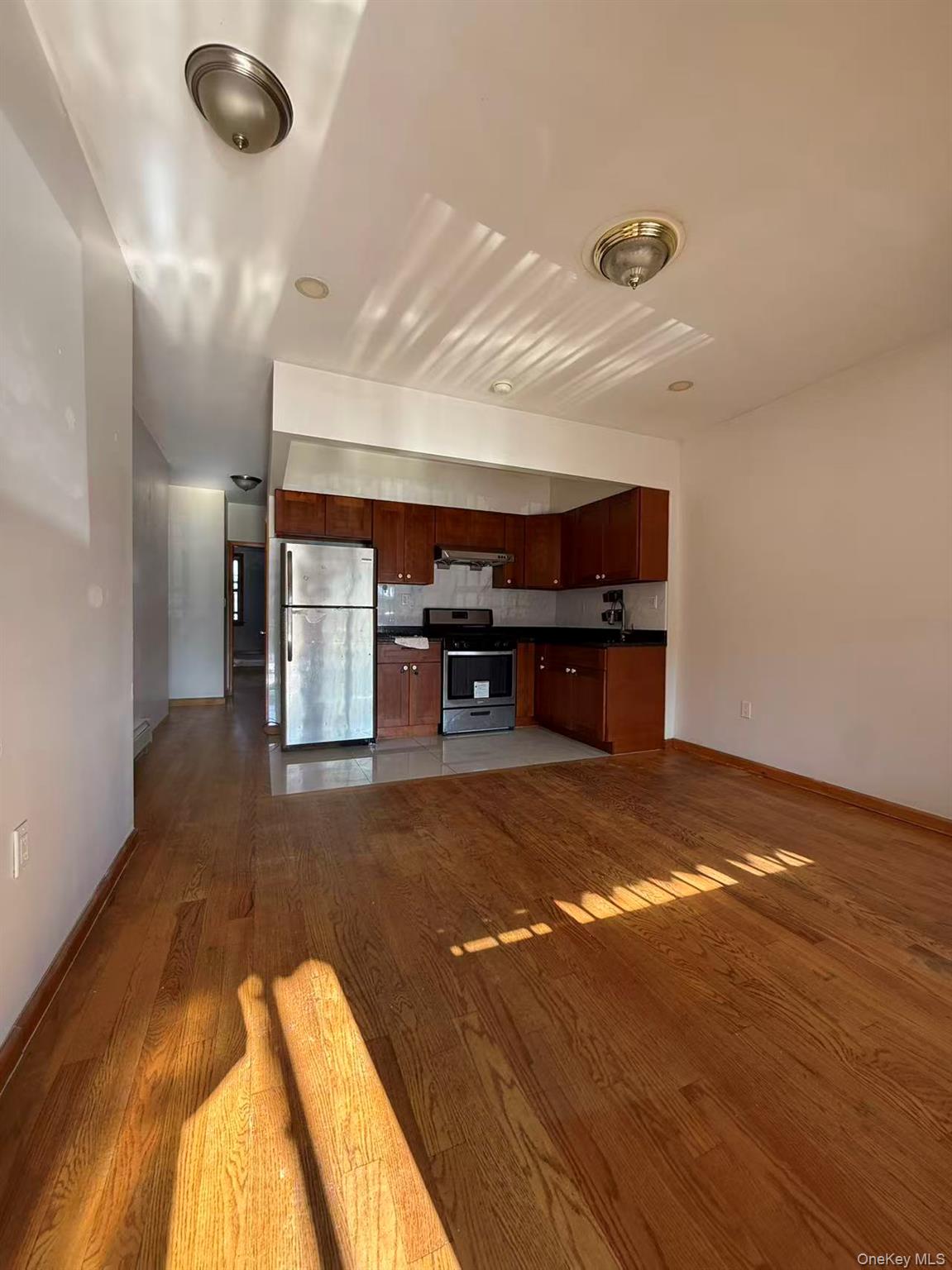 146-27 61st Road Queens, NY 11367 - Photo 17 of 17 Kitchen featuring stainless steel appliances, dark countertops, dark wood-type flooring, open floor plan, and ventilation hood