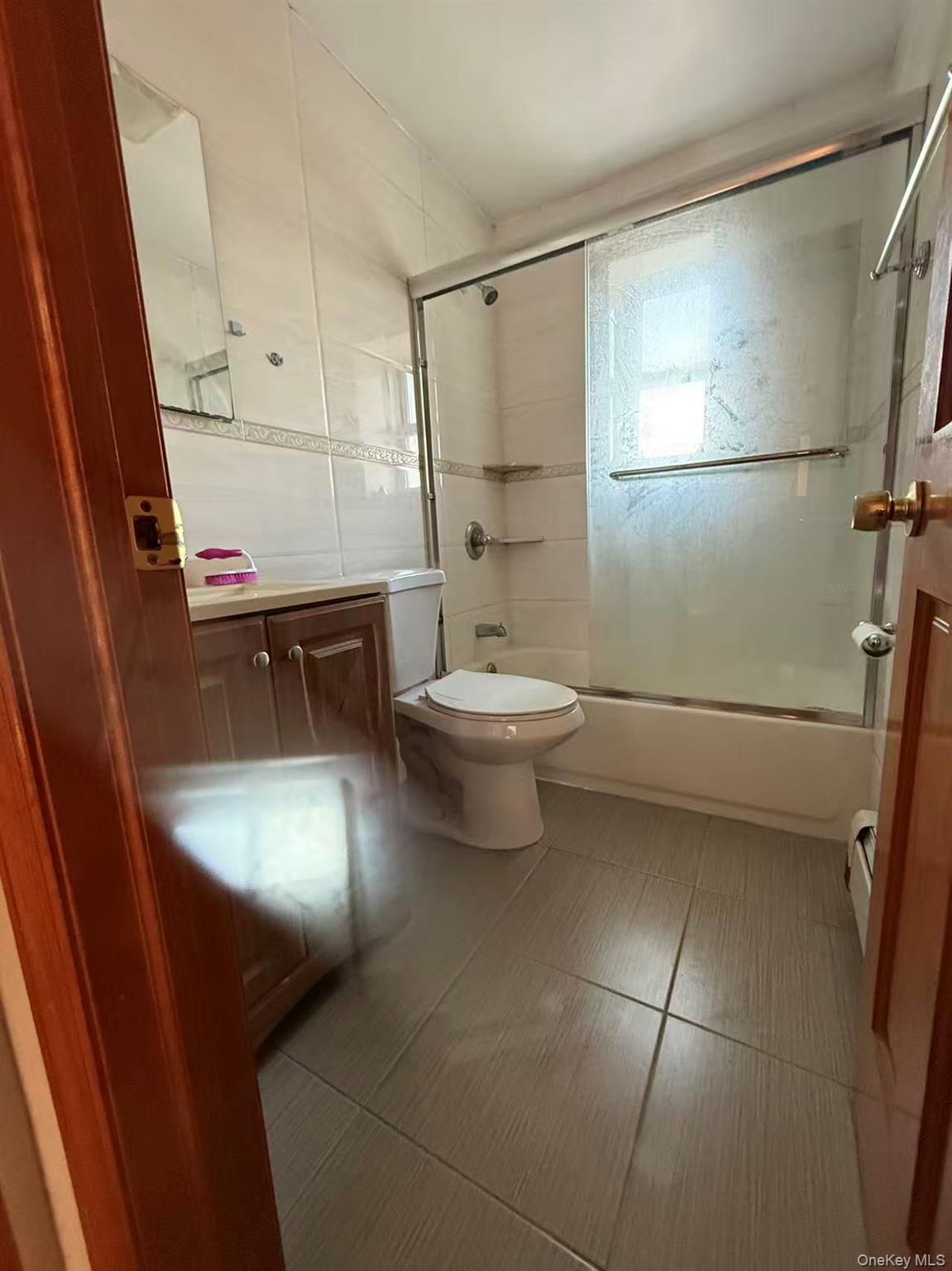146-27 61st Road Queens, NY 11367 - Photo 7 of 17 Full bathroom featuring vanity, bath / shower combo with glass door, and tile walls