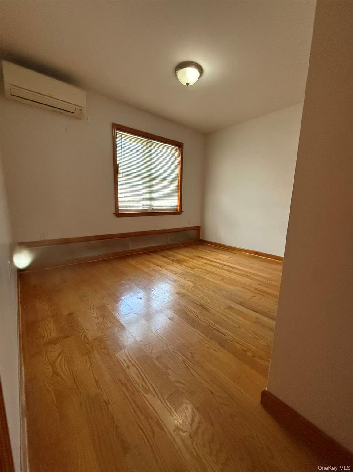 146-27 61st Road Queens, NY 11367 - Photo 8 of 17 Unfurnished room with a wall unit AC and light wood-style flooring