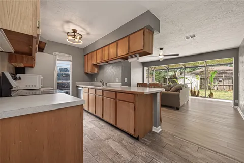 a kitchen with stainless steel appliances granite countertop a stove a sink dishwasher and a refrigerator with wooden floor