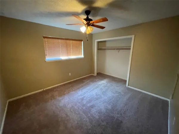 an empty room with a ceiling fan and window