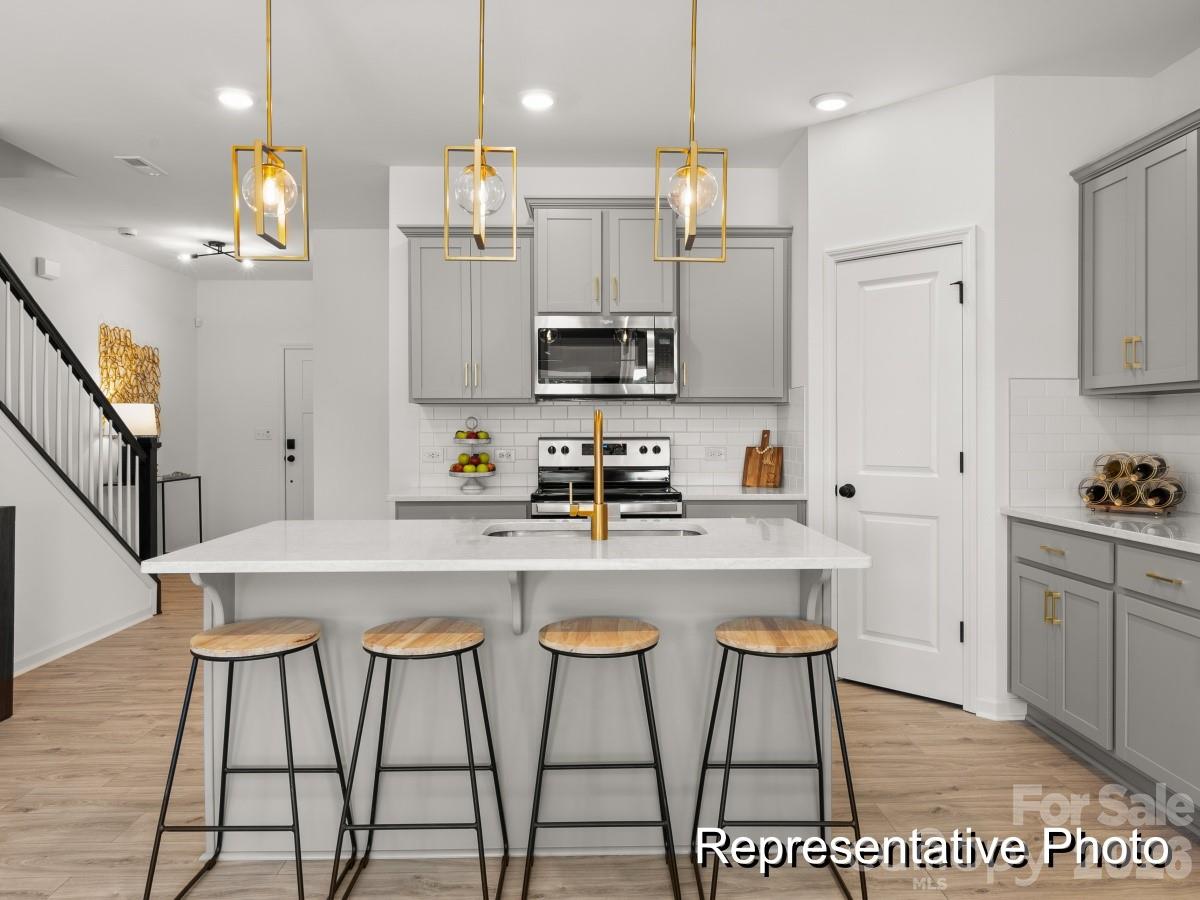 325 Drawbar Drive, Unit 98 Clover, SC 29710 - Photo 5 of 17 a kitchen with stainless steel appliances granite countertop a stove a refrigerator a sink a dining table and chairs with wooden floor