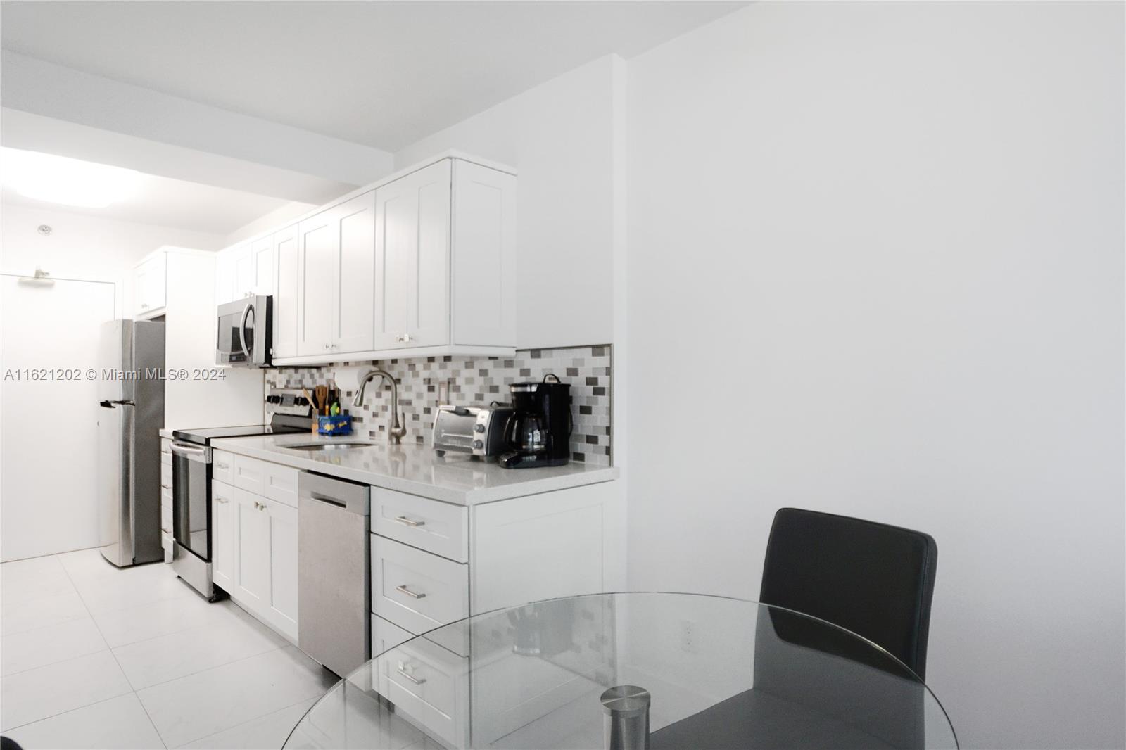 100 Lincoln Road, Unit 436 Miami Beach, FL 33139 - Photo 7 of 11 a kitchen with stainless steel appliances white cabinets and a stove top oven