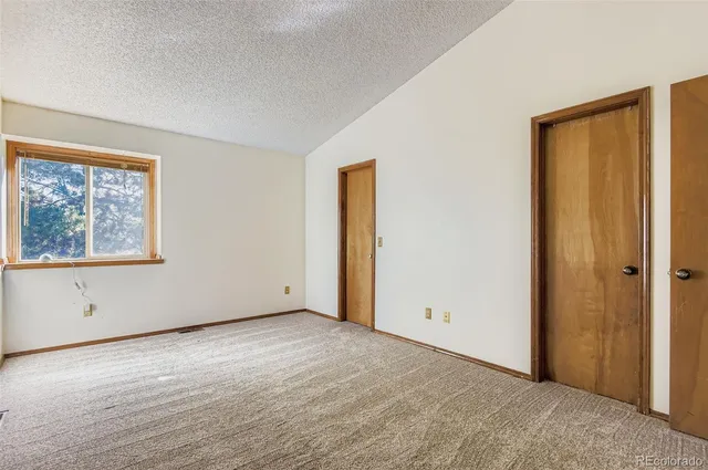 a view of an empty room with window and closet area
