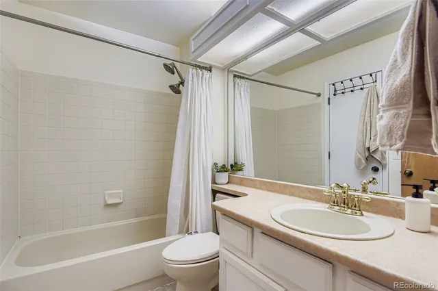 a bathroom with a bathtub shower sink vanity mirror and toilet