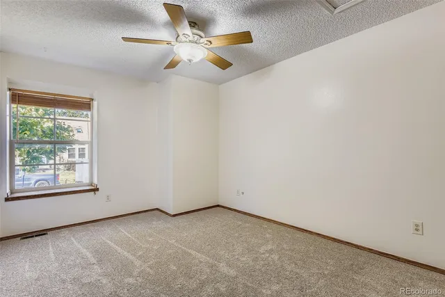 an empty room with a window and a ceiling fan