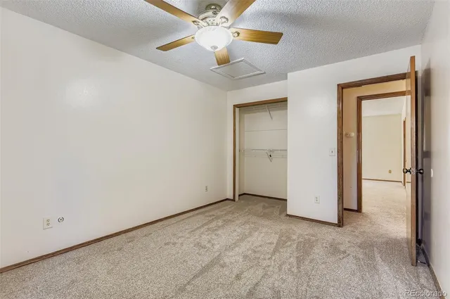 an empty room with closet and a chandelier fan
