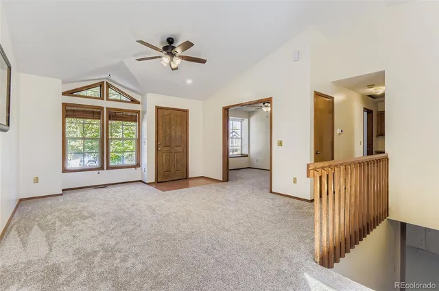 an empty room with ceiling fan and windows