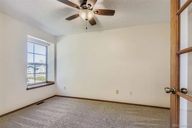 an empty room with windows and fan