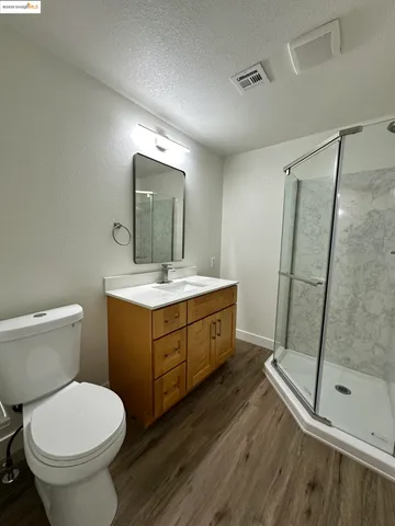 an empty room with wooden floor kitchen view and windows