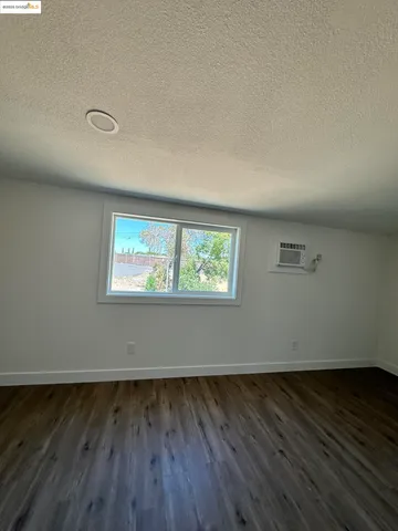 a view of an empty room with wooden floor and stairs