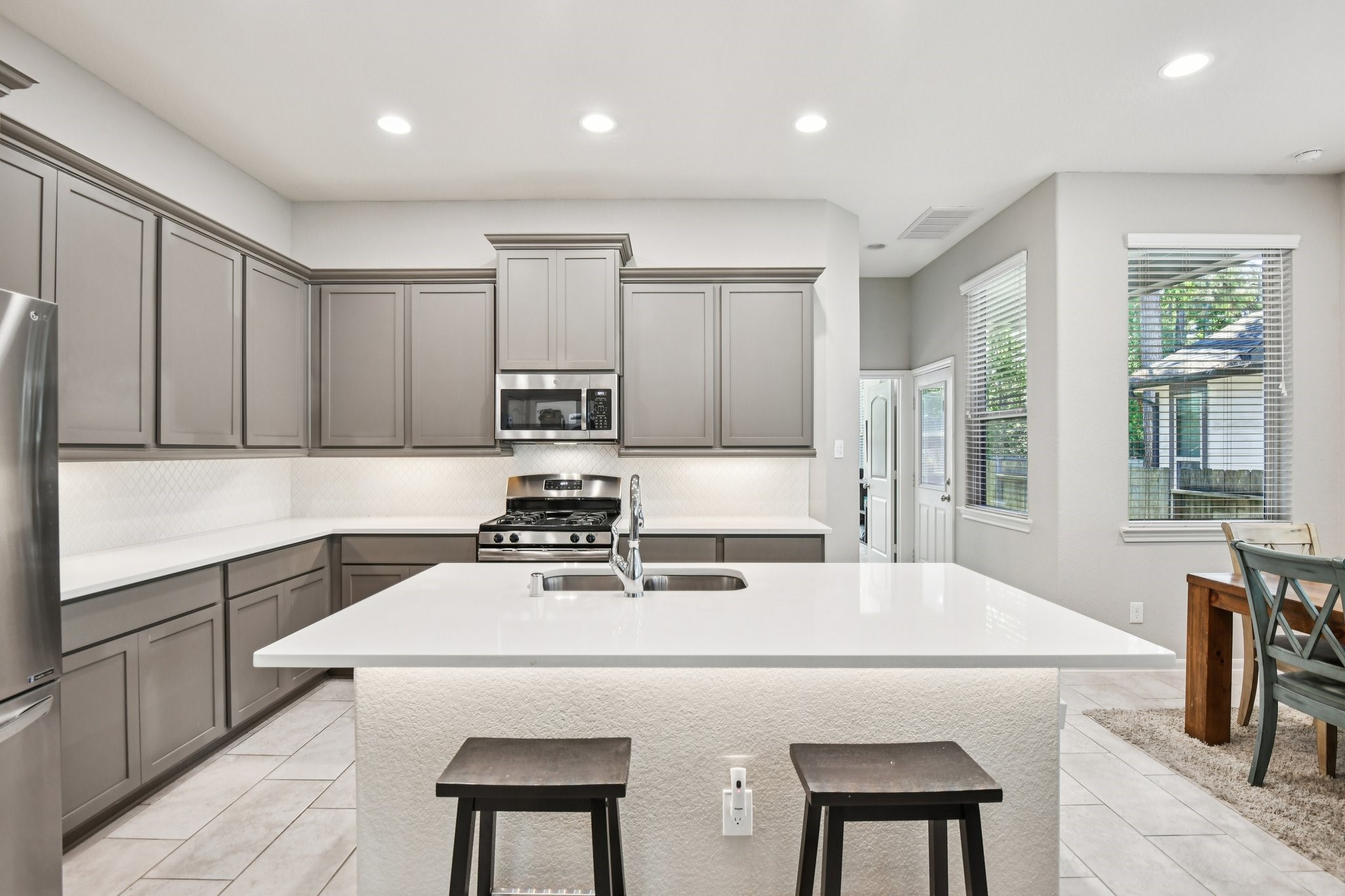 230 Biltmore Loop Montgomery, TX 77316 - Photo 14 of 39 Bright, inviting kitchen includes quartz countertops, beautiful backsplash and undercabinet lighting!