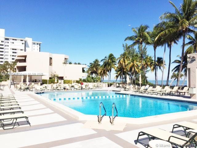 201 Crandon Boulevard, Unit 636 Key Biscayne, FL 33149 - Photo 30 of 53 a view of a swimming pool with a lawn chairs and palm tree