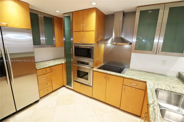 a kitchen with stainless steel appliances granite countertop a refrigerator a stove and a sink with wooden floor