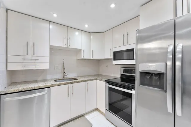 a kitchen with granite countertop white cabinets and stainless steel appliances