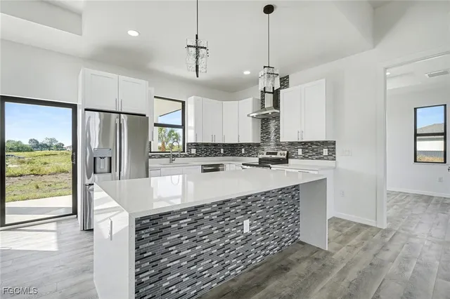 a large kitchen with kitchen island a large counter top space stainless steel appliances and a center island