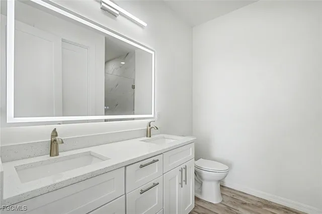 a bathroom with a granite countertop sink a toilet and a mirror