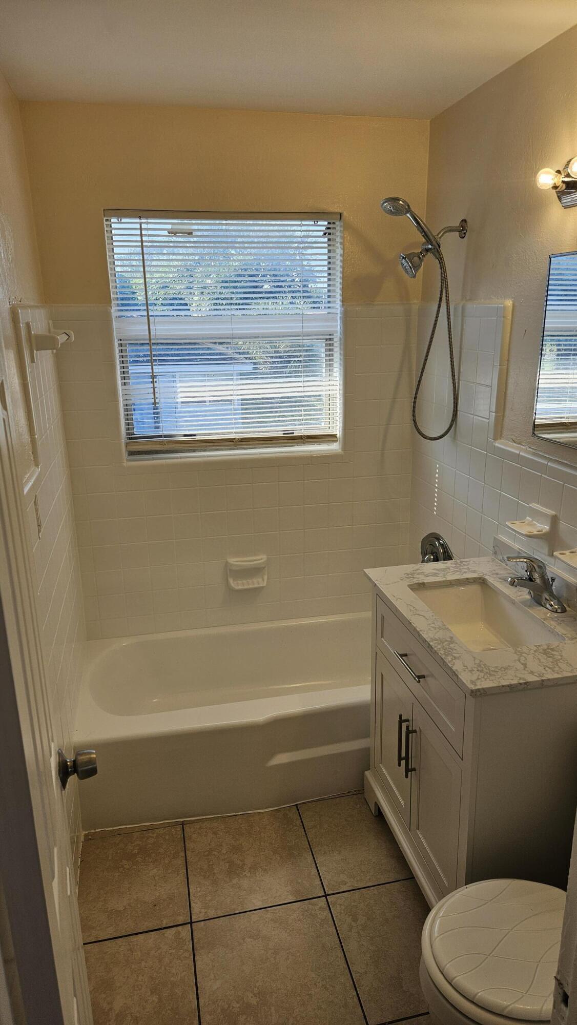 a bathroom with a granite countertop sink a toilet and shower