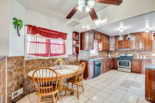 a kitchen with stainless steel appliances granite countertop a sink a stove a refrigerator cabinets and dining table
