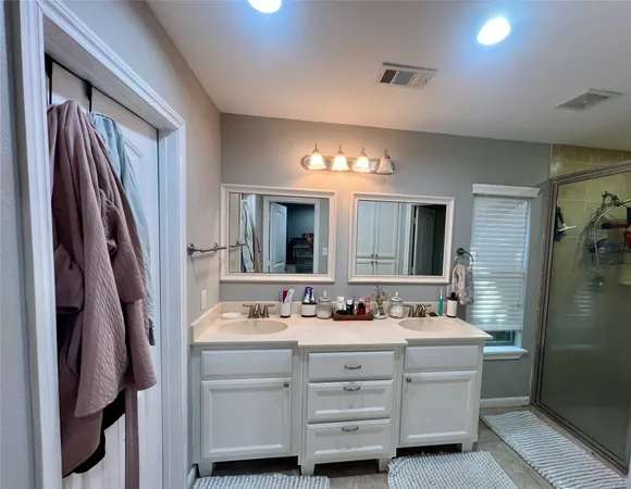 a bathroom with a double vanity sink a mirror and a shower