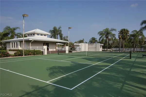 a view of a tennis ground with large trees