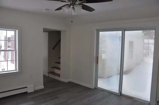 an empty room with wooden floor fan and windows