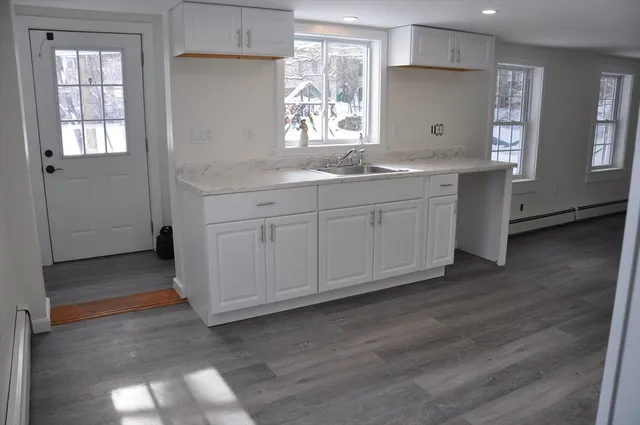 a kitchen with granite countertop white cabinets and sink