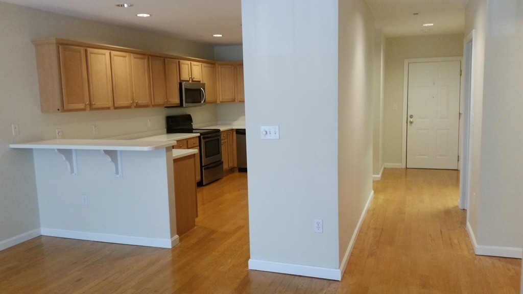 974 Main Street, Unit 25 Wakefield, MA 01880 - Photo 5 of 28 a view of a kitchen with a sink and dishwasher a refrigerator with wooden floor