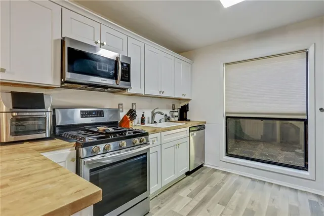 a kitchen with stainless steel appliances a stove a microwave a sink and cabinets