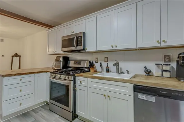 a kitchen with granite countertop white cabinets sink and stainless steel appliances