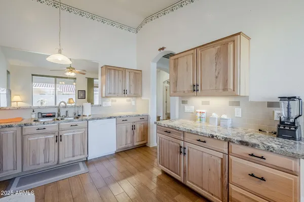a kitchen with stainless steel appliances granite countertop a sink a stove and a microwave oven with white cabinets