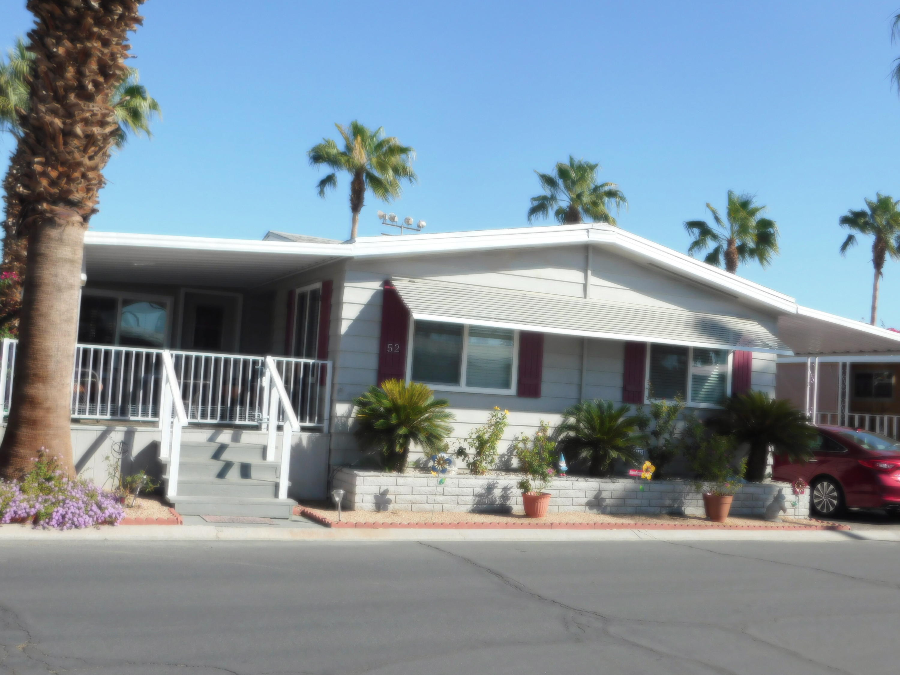 a view of a house with potted plants and a table and chair