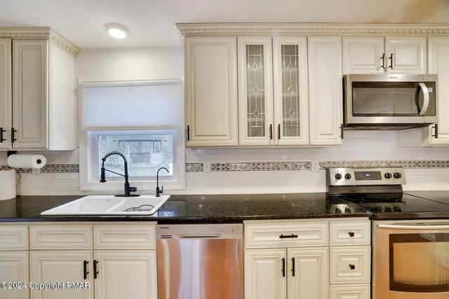 a kitchen with stainless steel appliances granite countertop a sink a stove and cabinets