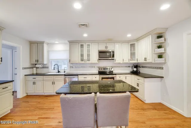 a kitchen with kitchen island granite countertop a stove sink microwave and cabinets