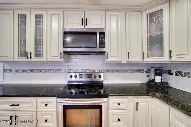 a kitchen with granite countertop a stove a microwave and cabinets