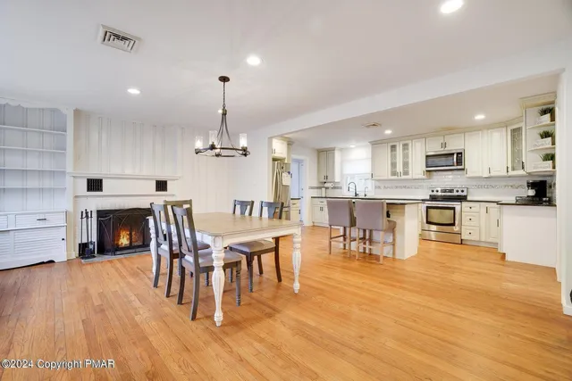 a living room with stainless steel appliances furniture a fireplace a kitchen island a stove and a wooden floor