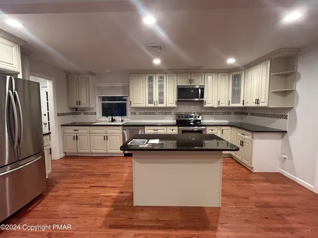 a kitchen with stainless steel appliances granite countertop a sink a stove a refrigerator cabinets and a kitchen island