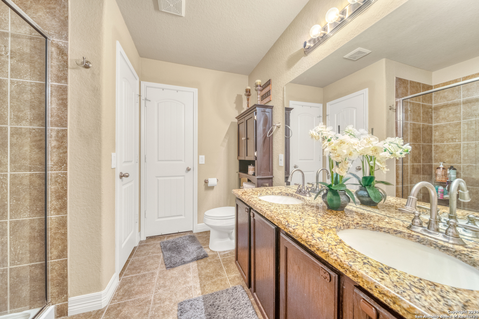 511 Fort Apache San Antonio, TX 78245 - Photo 21 of 32 a bathroom with a granite countertop sink a mirror and a shower