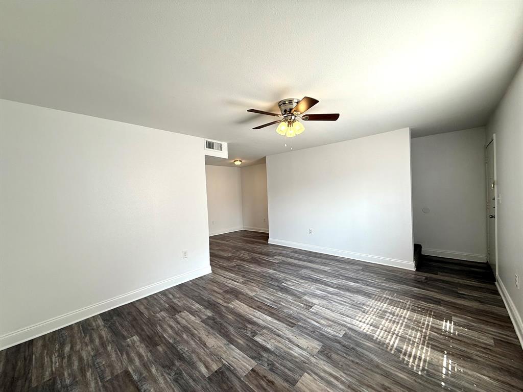 3650 Rickshaw Drive, Unit 3656 Dallas, TX 75229 - Photo 2 of 20 Empty room with dark wood finished floors and a ceiling fan