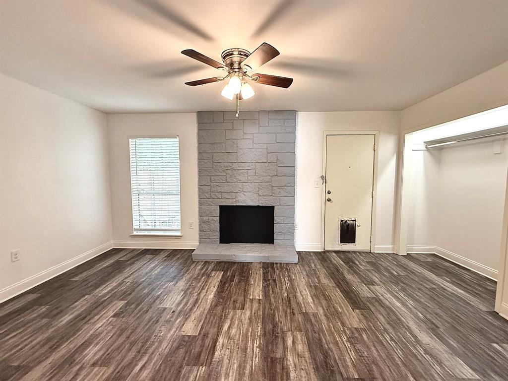 3650 Rickshaw Drive, Unit 3656 Dallas, TX 75229 - Photo 7 of 20 Unfurnished living room featuring dark wood-style floors, a fireplace, and ceiling fan