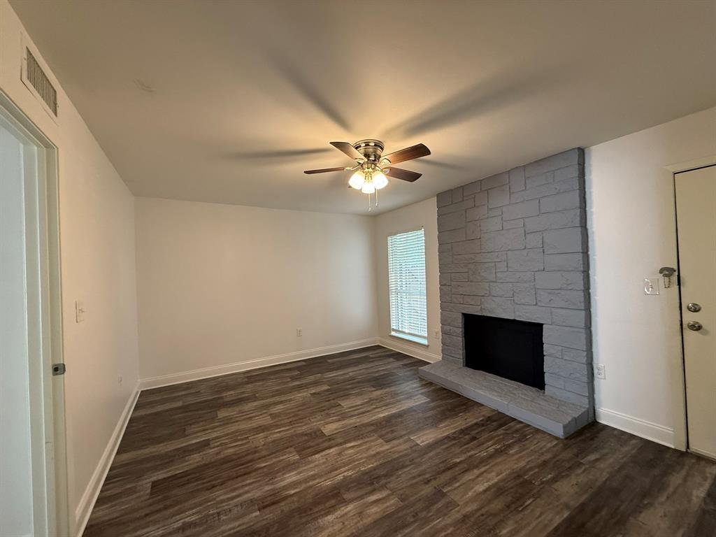 3650 Rickshaw Drive, Unit 3656 Dallas, TX 75229 - Photo 8 of 20 Unfurnished living room featuring a fireplace, dark wood-type flooring, and a ceiling fan