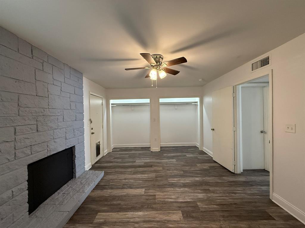3650 Rickshaw Drive, Unit 3656 Dallas, TX 75229 - Photo 9 of 20 Unfurnished living room with dark wood-style flooring, a stone fireplace, and a ceiling fan