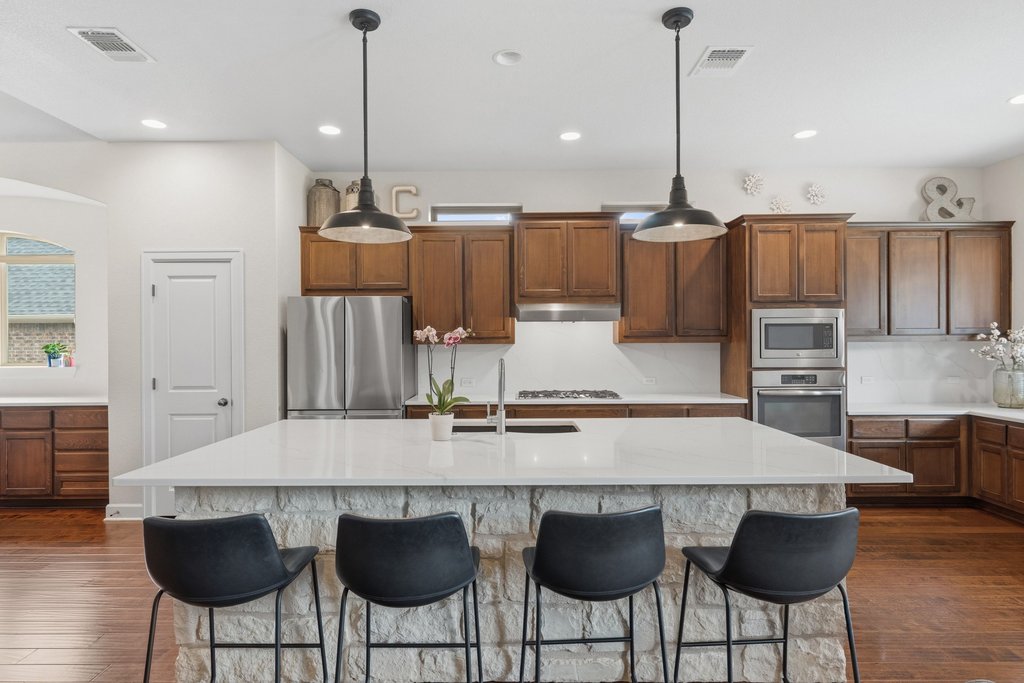 558 Merion Drive Austin, TX 78737 - Photo 12 of 40 a kitchen with stainless steel appliances a table and chairs in it